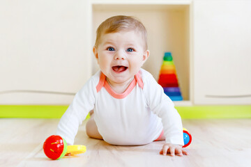 Cute happy smiling baby playing with colorful rattle toys. New born child, little girl looking at...