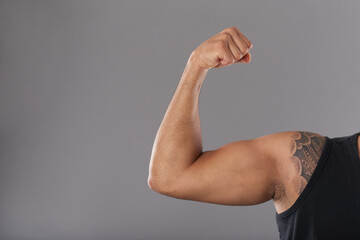 Close-up image of strong muscular young man flexing biceps
