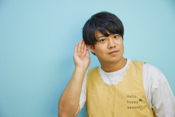 コピースペースに向かって耳を傾けるエプロンを着たアジア人男性