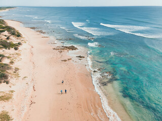 Drone view of men with fishing rods walking along coast