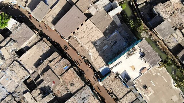 Top aerial drone movement shot of the closely packed urban slums or shanty town housing situated next to sewage in suburban part of the Mumbai city
