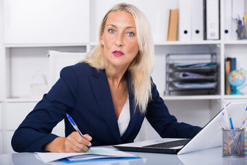 Portrait of mature serious business woman at working place in office