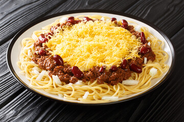 American food Cincinnati chili with spaghetti, cheddar cheese and beans close-up in a plate on the table. horizontal