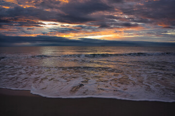 Obraz premium A beautiful and cloudy sunrise from the shore of a beach