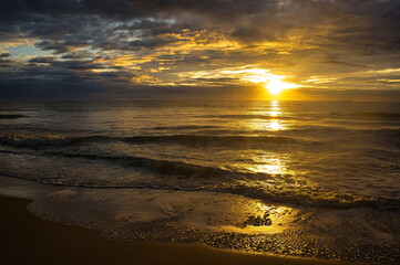A beautiful and cloudy sunrise from the shore of a beach