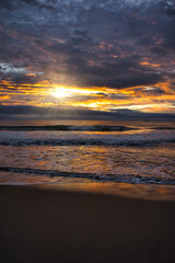 Fototapeta na wymiar A beautiful and cloudy sunrise from the shore of a beach