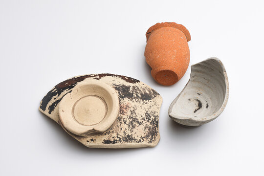 Archeologia: frammenti di vasetti e ciotole di epoca romana di vari materiali e colori isolate su fondo bianco