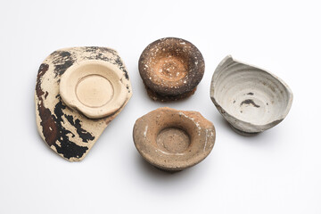 Archeologia: frammenti di vasetti e ciotole di epoca romana di vari materiali e colori isolate su...