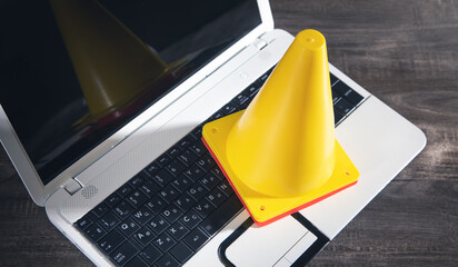 Yellow traffic cone on laptop keyboard.
