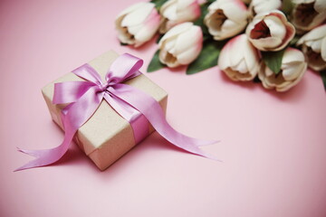 Gift boxes with pink ribbon and tulip flower bouquet on pink background