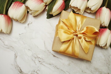Gift boxes with gold ribbon and tulip flower bouquet on marble background