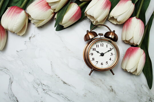 Vintage alarm clock and tulip flower bouquet on marble background