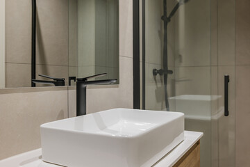 Close-up of white sink with black faucet and mirror. Interior of modern style bathroom in refurbished apartment.
