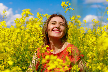 Young pretty woman in a colored dress on Lightning cheerful yellow background blooming rapeseed...