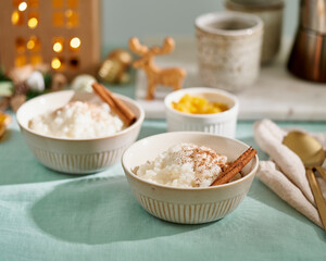 Christmas food. Rice pudding. French milk rice dessert. Christmas evening or night with cozy light of lamp Healthy Vegan diet with coconut milk, cinnamon. Color linen textile, side view