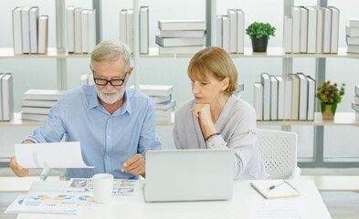 Fototapeta premium Caucasian old senior elderly successful marriage couple businessman and businesswoman entrepreneur working with company report graph chart paperwork documents together at desk with laptop computer