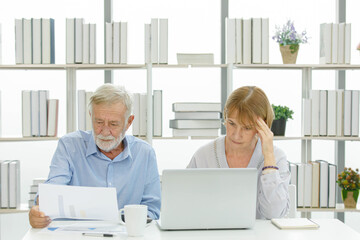 Caucasian old senior elderly successful marriage couple businessman and businesswoman entrepreneur working with company report graph chart paperwork documents together at desk with laptop computer