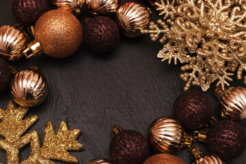 Fototapeta na wymiar Christmas decorative composition with gold shiny snowflakes, christmas golden balls on black wood background. Christmas or New Year concept. Festive Christmas background with baubles and copy space.