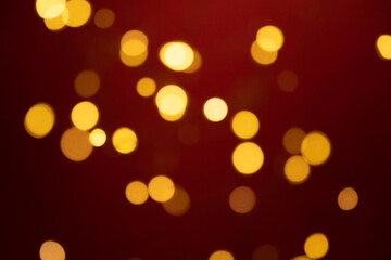 Bokeh golden lights background. Blurred lights festive garland on a red background