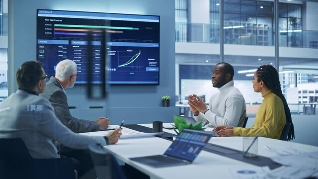 Multi-Ethnic Office Conference Room Meeting: Diverse Team of Professional Entrepreneurs, Investors Talk, Use TV Screen with infographics, Charts, Graphs. Businesspeople Discuss Investment Strategy