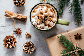 Obraz na płótnie Canvas Christmas holiday creative layout with purple cup of marshmallow hot chocolate, pine tree, and pine cones