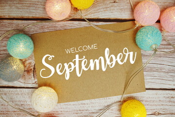 Welcome September card typography text with LED cotton ball on wooden background