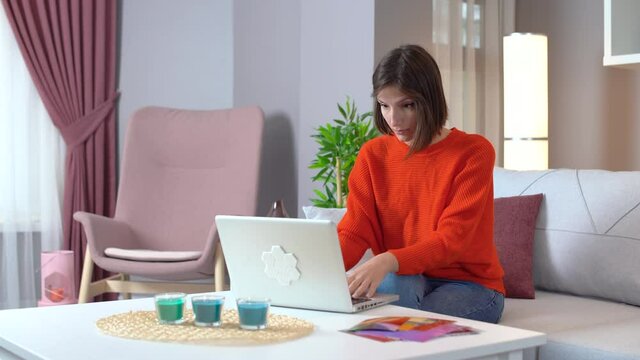 Surprised At The Computer. Rejoicing Woman. Young Attractive Woman In Orange Outfit Working On Laptop.