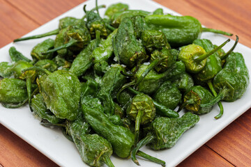 Baked green peppers with crystals of salt. Portion of fresh made Pimientos de Padron. Traditional spanish snack.