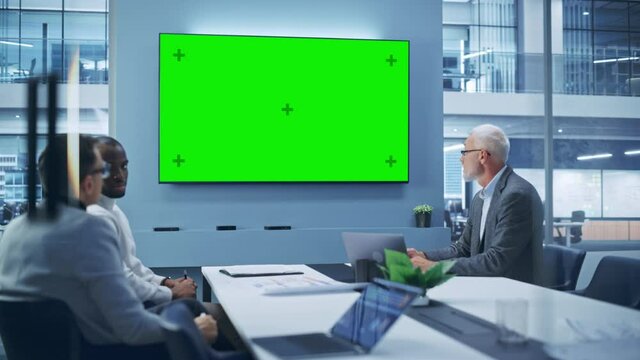 Office Conference Room Meeting using Video Call: Diverse Team of Successful Managers, Executives Talk, Use Green Screen Chroma Key TV. Businesspeople Work on Strategy for an e-Commerce Startup