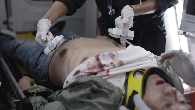 Paramedics using defibrillator for rescuing patient