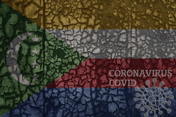 flag of comoros on a old metal rusty cracked wall with text coronavirus, covid, and virus picture.