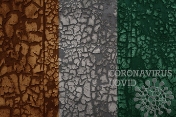 flag of cote divoire on a old metal rusty cracked wall with text coronavirus, covid, and virus picture.