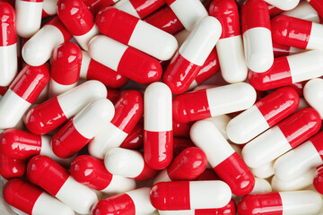 Medical medicinal Pills capsules are white and red in color as a background in full screen.