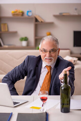 Old male employee drinking champagne at home