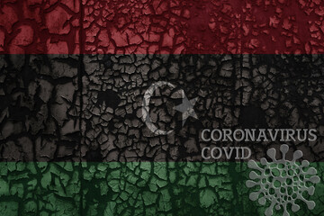 flag of libya on a old metal rusty cracked wall with text coronavirus, covid, and virus picture.