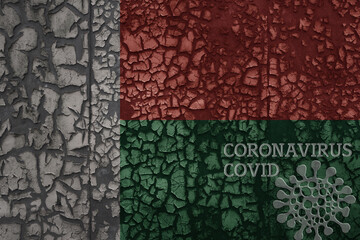 flag of madagascar on a old metal rusty cracked wall with text coronavirus, covid, and virus picture.