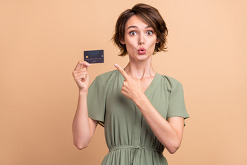 Naklejka premium Photo of excited crazy promoter lady direct finger credit card wear green dress isolated beige color background