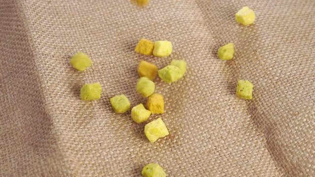 Dry organic herbs seasoning cubes falling on a rustic rough burlap.  Vegetable concentrated dehydrated ingredient. Close up. Vegetarian fast food concept. Slow motion. Rotation
