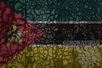 flag of mozambique on a old metal rusty cracked wall with text coronavirus, covid, and virus picture.