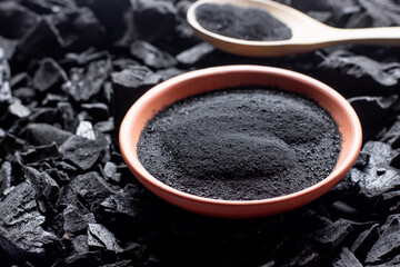 A large amount of fine charcoal is placed in a cup on top of a pile of charcoal.