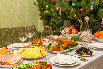 Festive Christmas served table against beautiful green pine tree decorated with many colorful new year toys. Xmas dinner, delicious food, christmas turkey. Winter holidays celebration at cozy home