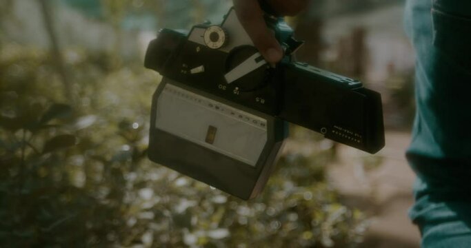 Slow motion shot of a man walking in a Plant nursery with a vintage camera