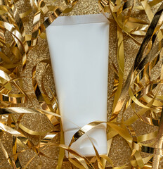 White unbranded tube with hand cream or face mask on glittering golden background. Beauty treatment presentation for holidays as a gift.