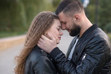 Fototapeta premium Young, stylish and attractive man and woman in the park in autumn. Couple in casual style, happy husband and wife.