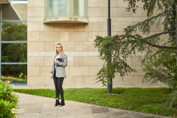 businesswoman waiting with agenda in hand for clients at the entrance of the offices