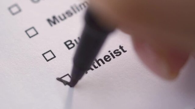 The person marks the atheist item in the list with a tick. Close-up. Questionnaire.