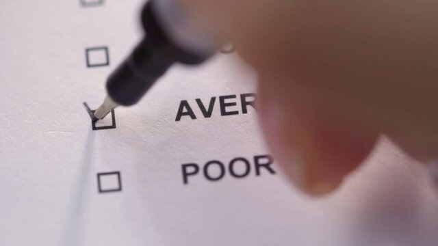 The person puts a check mark in front of the word average in the test. Close-up. Service quality assessment.