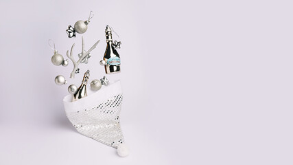 Creative Christmas composition with Santa Claus hat and flying decoration on bright white background. Minimal Xmas or New Year celebration concept. Minimal winter holidays idea. Banner with copy space
