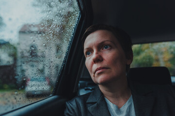Worried businesswoman waiting in the car and looking out the window during rain