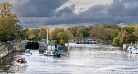 HAPTON COURT, LONDON, UK - Circa 2021 October Boats coming out of a lock on the river Thames with a...